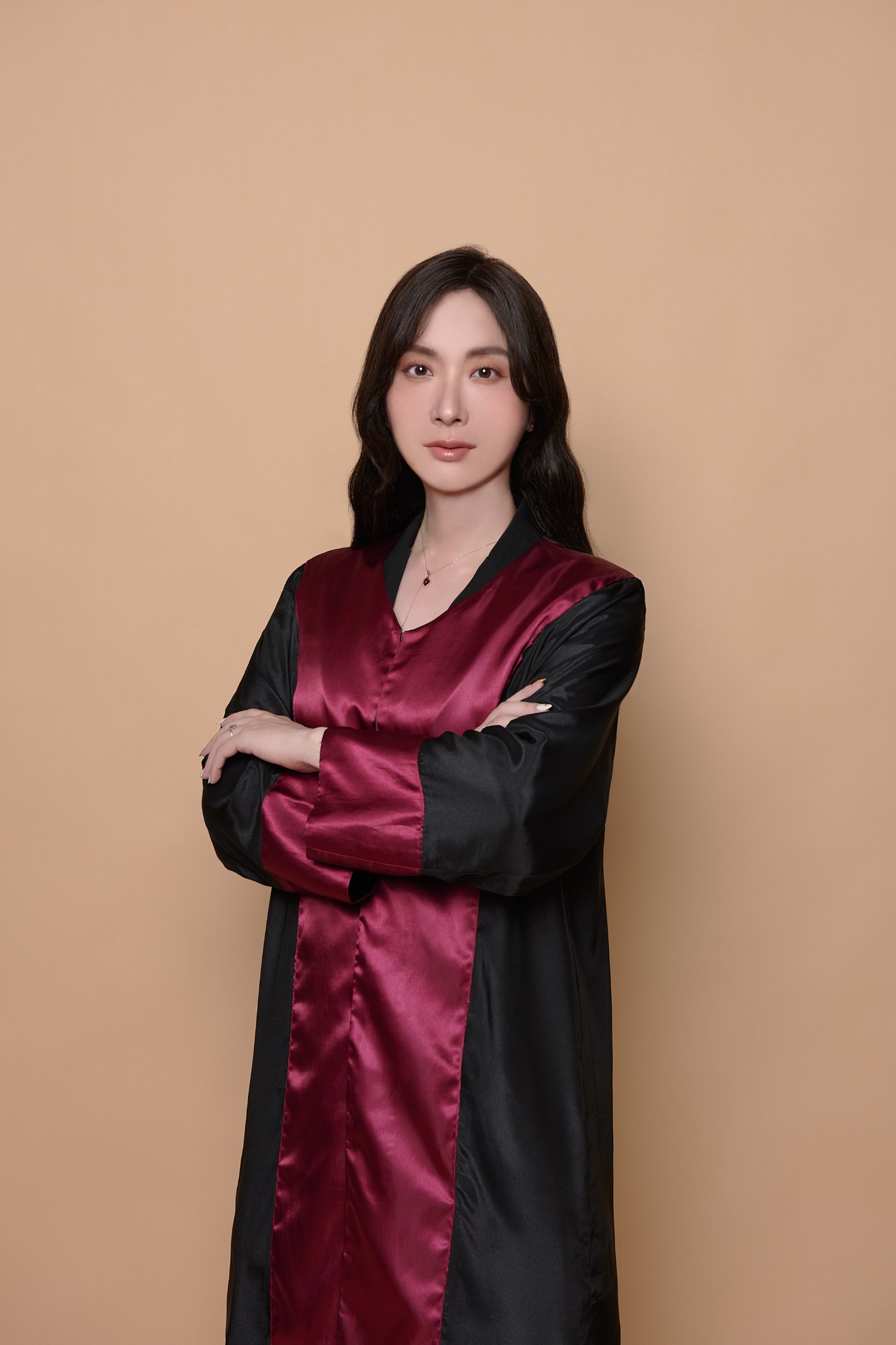 陳樂涵身穿黑色與酒紅色法袍，雙手抱胸的形象照