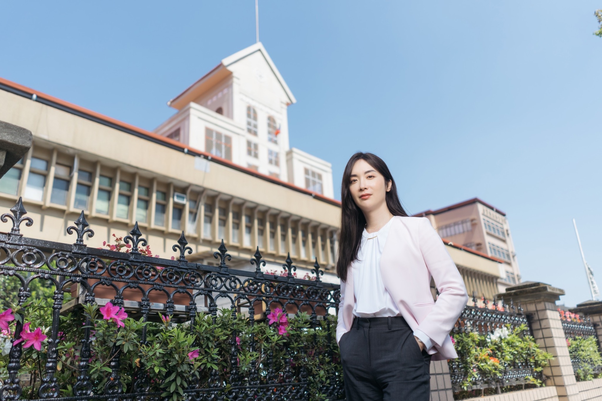 陳樂涵身穿淺色西裝，在藍天下與建築物前的戶外形象照
